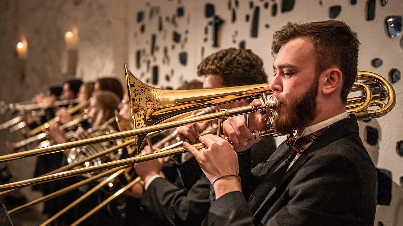 Trombone players performing as part of brass ensemble.